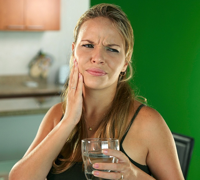 Woman in need of restortive dentistry holding cheek in pain