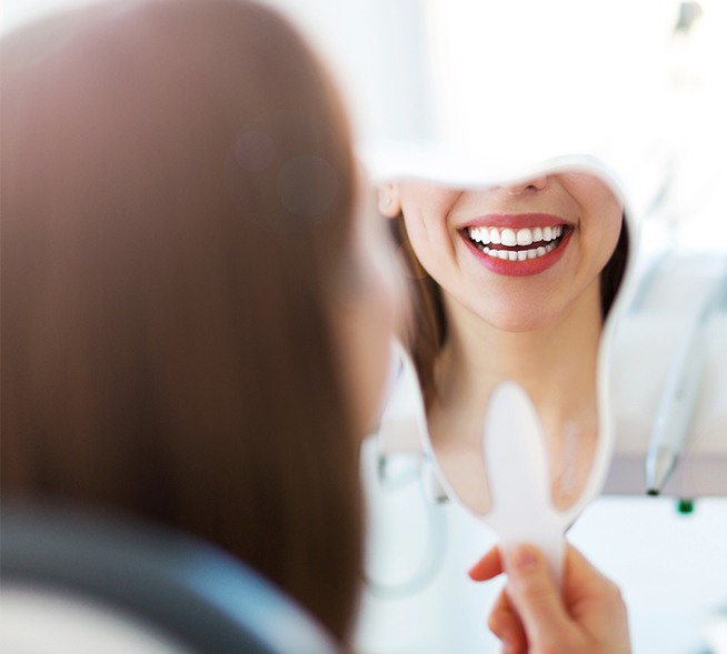 Woman looking at smile makeover in mirror