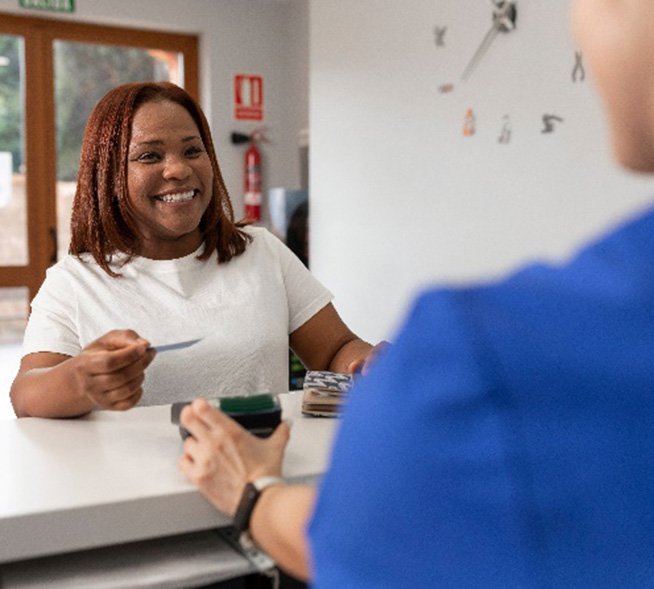 Smiling woman using credit card to pay for dental care