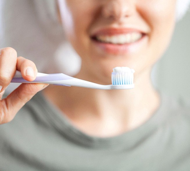 Close-up of a woman holding a toothbrush with toothpaste
