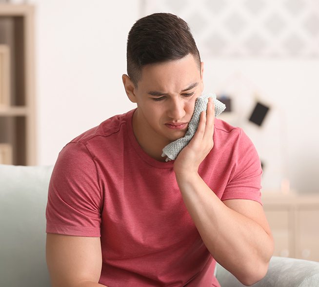 Man in pain holding cold compress to cheek