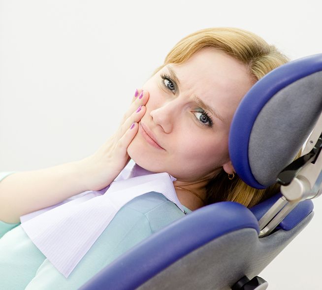 Woman at emergency dentistry appointment holding cheek
