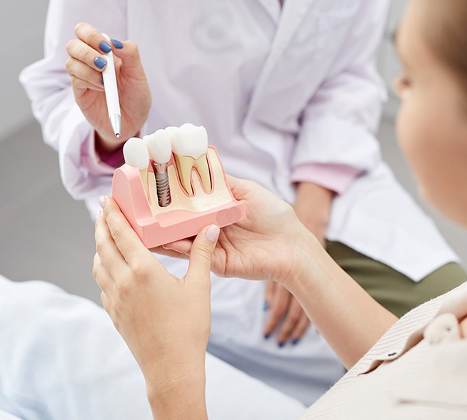 Dentist showing patient a dental implant model