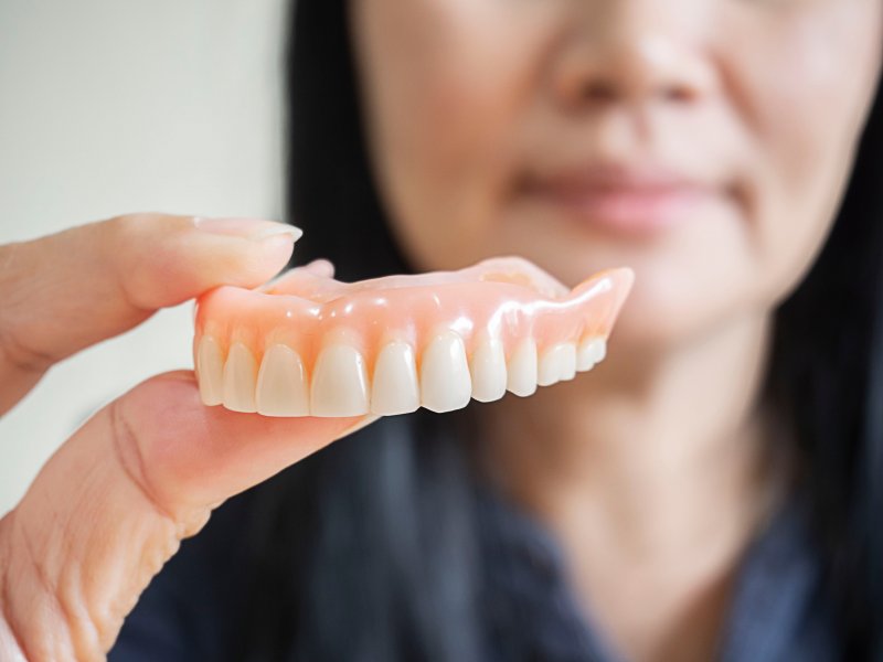 A denture being held by a young adult