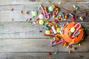 Candy surrounding Halloween bucket on a wooden table